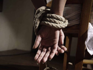 Young woman tied to a chair in a empty room, hands close up