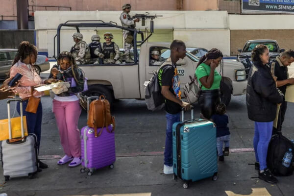 Migrantes de distintas nacionalidades hacen fila para ingresar a Estados Unidos vía la garita de Chaparral, Tijuana, en el estado mexicano de Baja California.