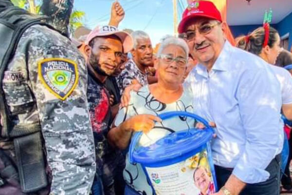 El senador por la provincia Hato Mayor, Dr. Cristóbal Castillo, entregando kits alimenticios en compañía de agentes policiales. FOTO: Fuente externa