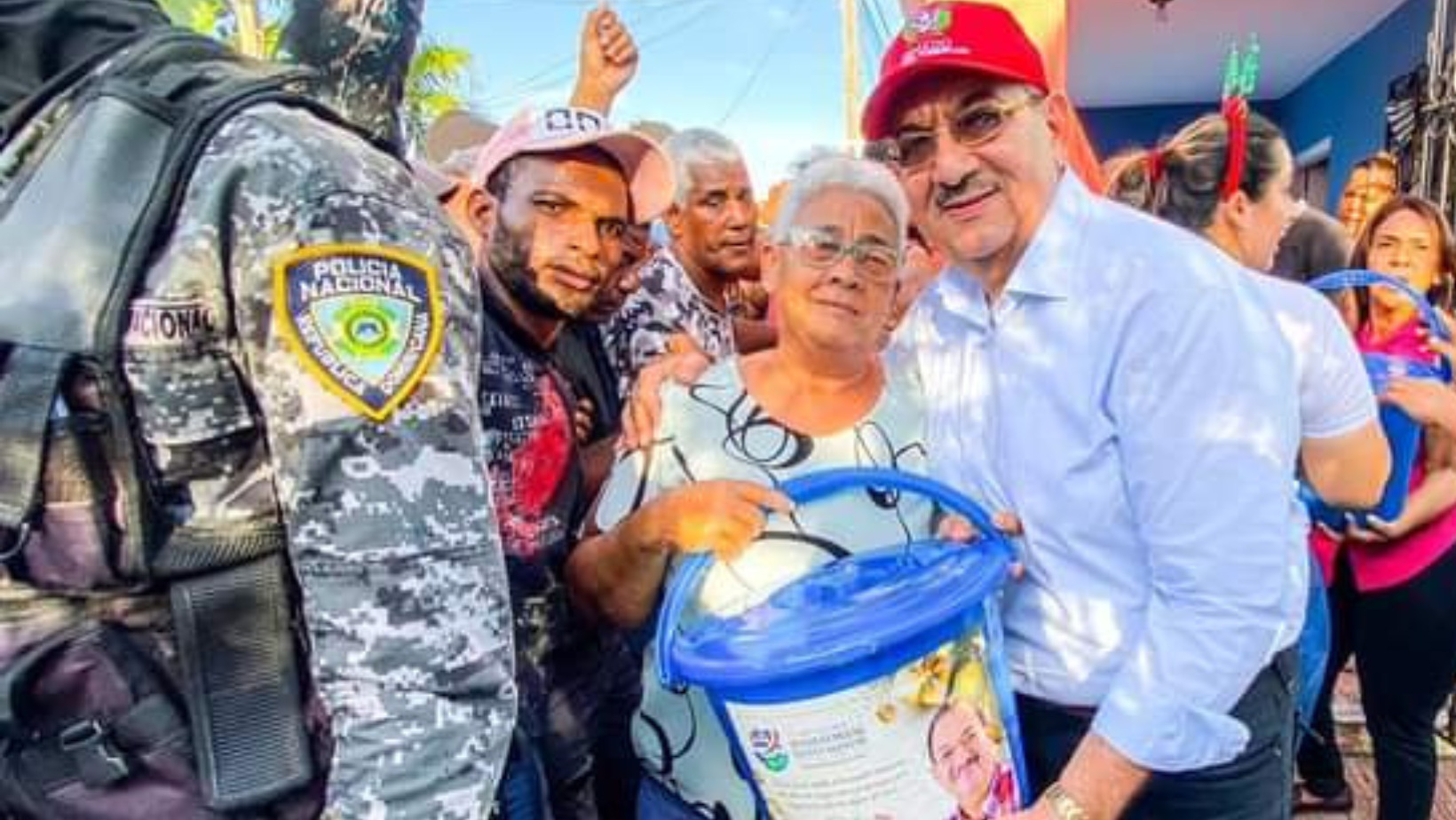 El senador por la provincia Hato Mayor, Dr. Cristóbal Castillo, entregando kits alimenticios en compañía de agentes policiales. FOTO: Fuente externa