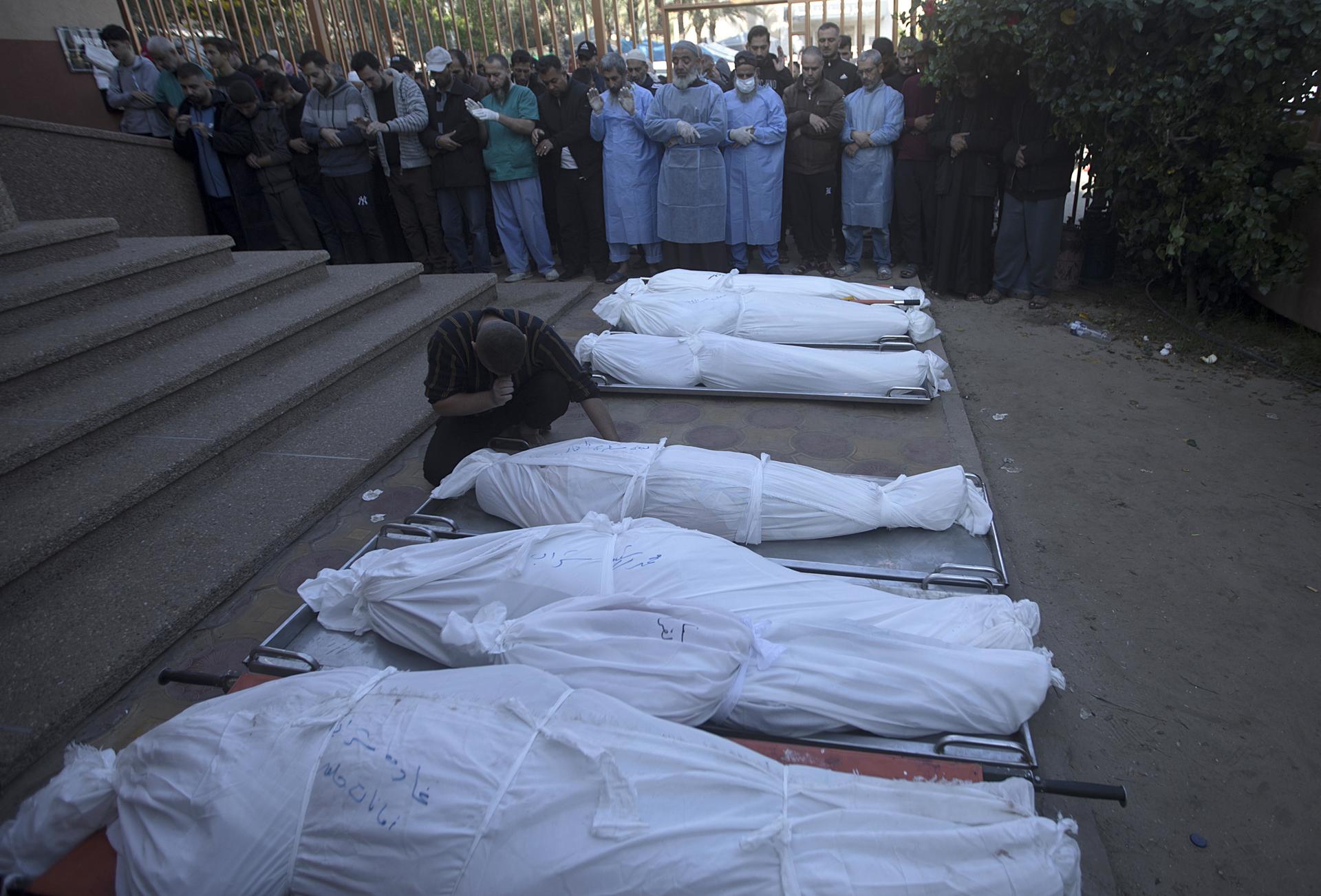 Familiares de fallecidos en Gaza rezan frente a sus cuerpos. Foto: fuente externa.