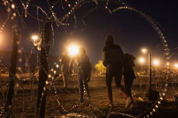 Migrantes cruzan un hueco en una valla de serpentina metálica, cerca del muro fronterizo entre México y Estados Unidos en El Paso, Texas. Foto: fuente externa.