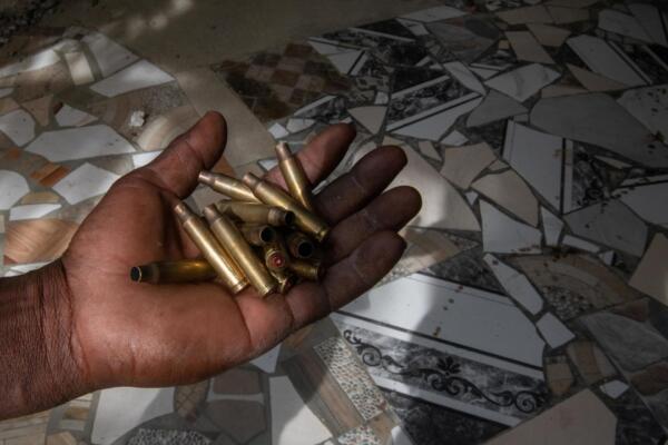 Un empleado muestra casquillos de balas en la puerta del hospital del populoso barrio de Cité-Soleil, en Puerto Príncipe, Haití. Foto: fuente externa.