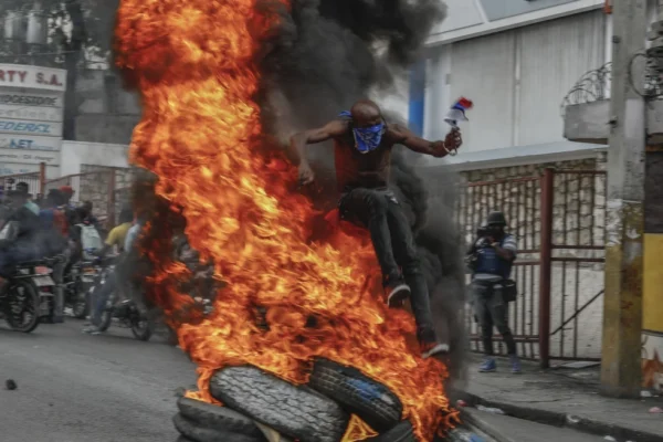 Un manifestante brinca por encima de numático en llamas durante una protesta contra el primer ministro haitiano Ariel Henry. / Fuente externa. 