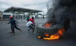 Los manifestantes agregan una llanta a una barricada en llamas durante una protesta contra las alzas en los precios del combustible y para exigir que el primer ministro haitiano Ariel Henry renuncie, en Puerto Príncipe, Haití, el viernes 16 de septiembre de 2022. © AP/Odelyn Joseph
