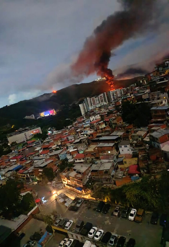 Incendio en Fuerte Tiuna, el mayor complejo militar de Venezuela, visto a distancia tras una serie de explosiones en Caracas el 3 de enero de 2026. (AFP)