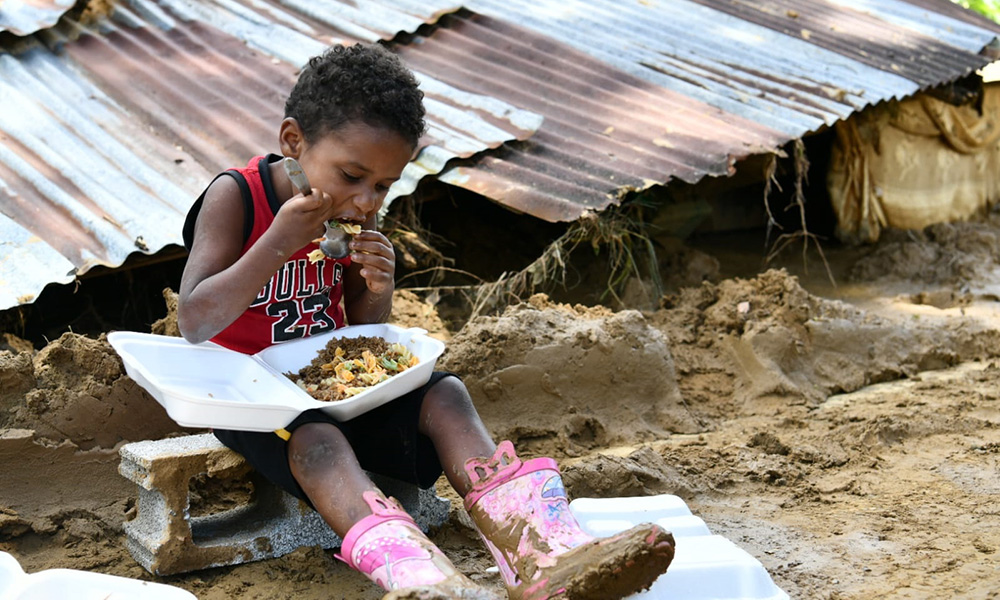 Un niño almuerza en medio del lodo dejado por las inundaciones. Foto: Ricardo Flete.